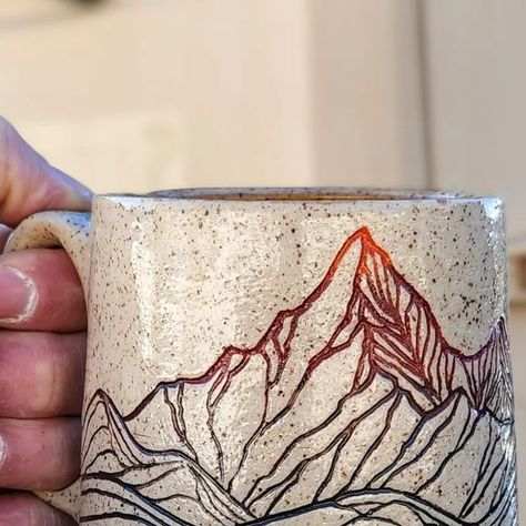 Ty Brookhart on Instagram: "Looking through the archives as I plan my year in the studio. These mountain mugs were a fan favorite. I really never tire of them either because carving them is like taking an imaginary backcountry trip - there's a lake behind that ridge fed by the snowmelt from that ragged peak, and with a little luck we'll be eating trout cooked on the coals from the fire.... Maybe it's a bit Bob Ross of me, but honestly, I watched him a lot on PBS as a kid; there were only 3 channels on our 13 inch TV. . . . . #mugshotmonday #mountainmade #coffee #coffeemug #sgraffito #modernmaker #waketomake #madeincolorado #art #design #designisinthedetails #americanartisan #designermaker #madeintheusa #claycarving #handmadecurator #design #designer #lovedesign #designlover #artanddes Mountain Carving Pottery, Carving Pottery Mugs, Sgraffito Mountains, Mountain Mug Pottery, Scraffito Mug, Sgraffito Designs Flowers, Simple Sgraffito Designs, Sgraffito Mug, Mug Shapes Pottery