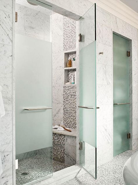 Create a fashionable seat that draws the eye inside your walk-in shower. This shower's interior boasts an arresting interplay of square and mosaic tiles that repeats down the face of the built-in bench, conveniently situated below a pair of toiletry niches. A solid slab of marble overhangs the bench base to magnify the seat's impact. Shower And Water Closet Side By Side, Fogged Shower Door, Fogged Glass Shower Door, Opaque Shower Door Ideas, Walk In Showers With Pony Walls, Tinted Shower Glass Doors, Opaque Shower Glass, Frosted Glass Shower Door Walk In, Opaque Shower Doors