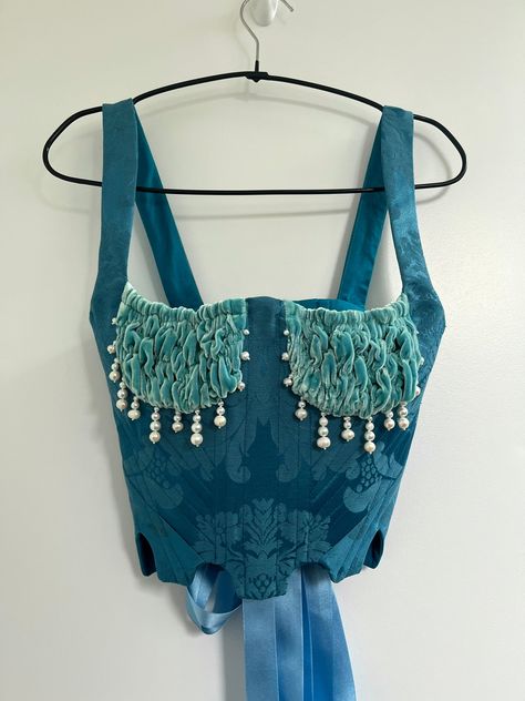 Made-to-order & historically inspired bustier. Corseted bodice in teal blue brocade, boned with a mixture of polyester and steel boning.  You have the options of 2 shapes for this piece, the Scalloped Hem (photo 1) or Curved Hem (photo 2) Soft aqua cups in silk velvet, ruched with elastic for a stretchy and comfortable fit in the balconette style. Embellished by hand with a combination of freshwater and glass pearl beading to create organic droplets around the bust.  Lace up back fastened with s Ballroom Dance Outfits, Velvet Corset, Blue Corset, Corset Bustier, Corset Lingerie, Bustier Top, Blue Lagoon, Bustiers, Silk Velvet