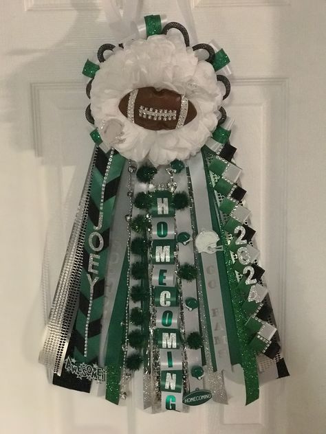 Mum, green, black, and white ribbons with a foot all in the middle of the flower Green Black And White Homecoming Mum, Green And White Mums Homecoming, Green Mums Homecoming, Purple Garter, White Garters, Football Mums, White Mums, 30th Birthday Decorations, Homecoming Mums Diy