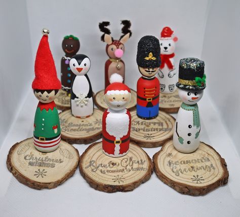 Hand painted Christmas peg dolls added to a wood slice base. Cute decor for every home at Christmas or to gift a dear one. Each peg doll is 6,5 cm/ 2,5 inches tall and the base has another 0,5 cm/ 0,2 inches, but decoration might be taller if it has a added hat. A wood slice base is aprox. 6-7 cm wide and each have something written on them with silver. All peg dolls have a layer of matte varnish for protection. These are unique decorations, only 1 of each available (8 in total): a penguin, a gingerbread man, a Santa Claus, a reindeer, a polar bear, an elf, a nutcracker and a snowman. Receive a FREE GIFT - cute pom pom gonk Christmas tree decoration when you buy minimum 2 peg doll decorations. Gonk`s hat may differ in color.  ** Note that these are not made as toys, but as home decor. Plea Christmas Peg Dolls Ideas, Elf Peg Doll, Christmas Peg Doll Ideas, Wood Block Christmas Crafts, Wooden Peg Doll Ideas, How To Paint Peg Dolls, Peg People Ideas, Peg Dolls Christmas, Christmas Peg Dolls