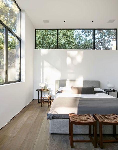 This modern master bedroom has a row of windows above the bed, with a second set of windows adding to the amount of the natural light the room receives. #ModernBedroom #BedroomDesign High Windows In Bedroom, Bedroom High Windows, High Window Above Bed, Bedrooms With Natural Light, Bedrooms With Two Windows, Windows In Bedroom Ideas, Natural Lighting Bedroom, Bedroom Window Above Bed, Ceiling Window Bedroom