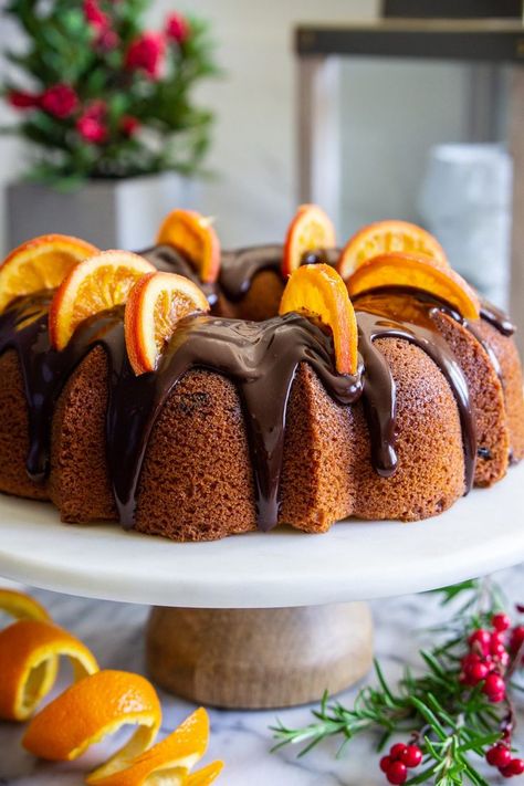 cranberry orange bundt cake with chocolate ganache on top, and dried orange slices on top, with an orange peal beside it Halloween Bundt Cake Ideas, Cranberry Orange Bundt Cake Recipe, Chocolate Cranberry Cake, Cranberry Orange Bundt Cake, Moist Lemon Pound Cake, Orange Peal, Baked Gifts, Infused Chocolate, Orange Bundt Cake