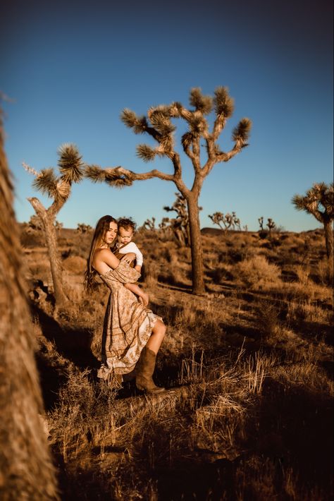 Beautiful brunette mother holding young toddler son wearing overalls in Joshua tree, California. Mother is holding son while being framed by to Joshua trees with direct sunlight. Mom is wearing dress by spell. Desert Photoshoot Ideas Family, Desert Family Photoshoot, Desert Family Photos, Mom Baby Pictures, Mother Daughter Photography Poses, Motherhood Photoshoot, Desert Photoshoot Ideas, Desert Photos, Daughter Photography