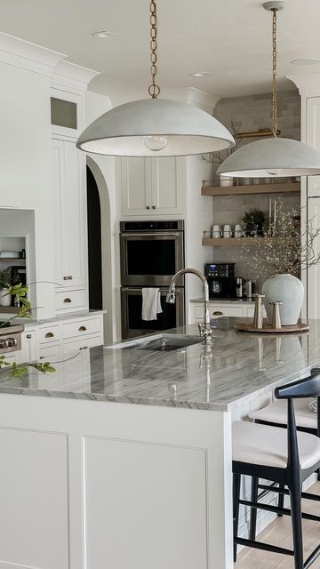 Megan West on Instagram: "I can’t believe our new kitchen was finished one year ago! We are obsessed with how it all came together from a style and function standpoint! This is definitely the area of the home we invested most heavily in! We love to cook and host and this is always our gathering place!  Paint color: BM White Dove Hardware: Top Knobs Pendants: Visual Comfort Countertops: Sea Pearl Quartzite  #homeremodel #remodeling #beforeandafterhomeedition #whitekitchencabinets #neutralhome #interiordesign #interiorinspiration #homeinspo" White Dove Kitchen Cabinets, Elliot Pendant, White Dove Cabinets, Paneled Fridge, Bm White Dove, Sea Pearl Quartzite, Megan West, White Oak Cabinets, Appliance Pulls