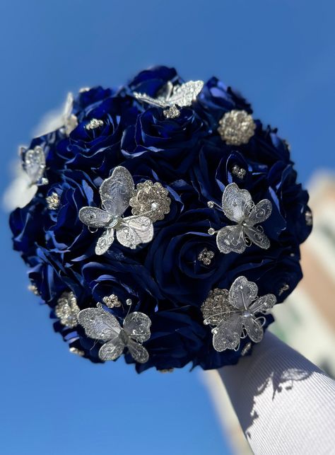 Handmade quinceañera bouquet with Royal Blue color shade of roses. Finished off with silver butterflies.  *Please note brooches can change in style based on availability*   Decor can be changed upon request.  *This is a made to order bouquet* Navy Blue Bouquet Quinceanera, Royal Blue Quinceanera Butterfly Theme, Royal Blue And Silver Quinceanera Centerpieces, Royal Blue Butterfly Quince Dress, Royal Blue Quince Doll, Royal Blue Quinceanera Ramo, Quincenera Dresses Blue And Gold, Royal Blue With Silver Quinceanera Theme, Royal Blue And Gold Butterfly Quinceanera Theme