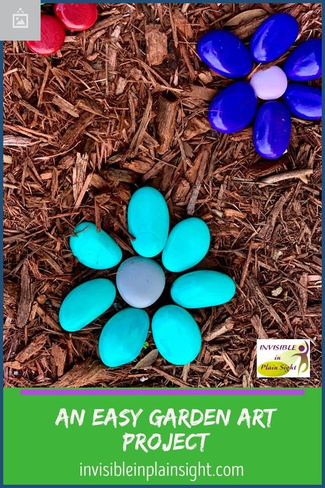 River rocks and acrylic paint are all you need to create these whimsical brightly colored flowers for a no-maintenance garden. Painted Rock Flower Garden, Painted Flower Rocks Garden Art, Rock Flowers In Garden Stone Art, Flower Rock Garden, Painted River Rocks Garden, Painted Rock Flowers In Garden, Painted Rock Landscaping Ideas, Painted Stones Flowers, Rock Flowers In Garden