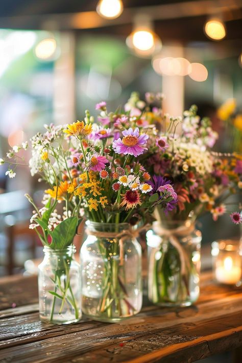 Discover the perfect blend of simplicity and elegance for your big day! 🌼💐 Our DIY wedding centerpieces feature vintage mason jars, handpicked wildflowers, and natural twine accents. Create a cozy, romantic atmosphere at your reception. #WeddingInspiration #RusticWedding #DIYBride #MasonJarDecor #WildflowerCenterpieces #VintageWeddings #SimpleElegance #RomanticDecor Wedding Flower Vases Reception Ideas, Wild Flowers In Mason Jars, April Centerpiece Ideas, Diy Wildflower Centerpieces, Wildflower Mason Jar Centerpieces, Wedding Flowers Summer Simple, Wildflower Table Arrangements, Potted Plants Wedding Centerpiece, Diy Center Piece Ideas