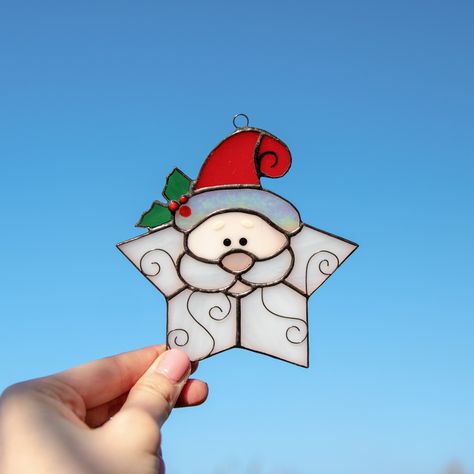 This adorable stained glass Santa snowflake is an essential part of Christmas decor as it can serve both as a window hanging and a New Year Tree decoration. In addition, it will serve as a fantastic gift for friends and relatives in the eve of Christmas holidays! Measurements: 4.7 x 4.5 inch (120 x 114 mm) This suncatcher is manufactured using L.C. Tiffany technique of copper foil. When manufacturing stained glass masterpieces, we use only the high-quality materials, such as:• 3 mm Spectrum Glass (USA) • 3 mm Wissmach Glass (USA) • Tin• Copper Foil• Black Patina• Wax⠀ We heartily advise you to wipe stained glass items of decor with a wet piece of clothing. Be sure that you will get your order in one piece, as we carefully pack stained glass products into special brand boxes. _____________ Christmas Stained Glass Ideas, Modern Christmas Tree Decor, Christmas Suncatchers, Window Measurements, Christmas Stained Glass, New Year Tree, Diy Stained Glass Window, Stained Glass Window Hangings, Stained Glass Patterns Free