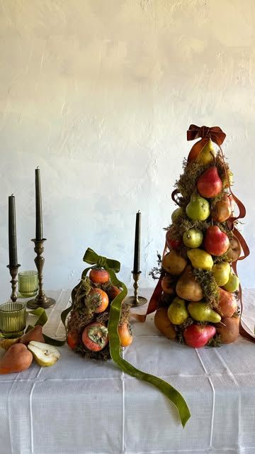 Steelcut | Wedding Florist on Instagram: "We’ve been feeling all things 90s nostalgia lately, so when a recent wedding resulted in leftover pears and persimmons we decided to dip our toes in vintage waters and try topiaries. 
This is a super easy centerpiece to make and you can chop up the fruit afterwards to use for baking or to freeze for smoothies 😋.
What do you think, can topiaries make a comeback or do they need to stay in the past? 🤔

Ingredients:
4 bags of rainbow pears from @traderjoes (could also be apples or a single variety of pear, and quantity is flexible, if you want to use less you can simply fill in with more moss)

8 persimmons from @traderjoes (could be any type of seasonal fruit that’s available to you) 

2 craft cones of different sizes (available at any craft store) Fruit Topiary Centerpieces, Sugared Fruit Centerpiece, Persimmon Arrangement, Leftover Pears, Fruit Topiary, Sugared Fruit, Christmas Pear, Fruit Cones, Topiary Centerpieces