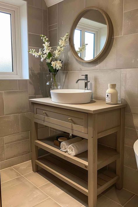 A small bathroom with a wooden vanity, vessel sink, round mirror, and floral decor, creating a warm and elegant atmosphere. Bathroom Vanity With Vessel Sink, Vanity With Vessel Sink, Small Bathroom Vanity, Beautiful Houses Exterior, Creative Bathroom Design, Neutral Bedroom Design, Utility Room Designs, Wooden Accent Wall, Elegant Bathroom Design