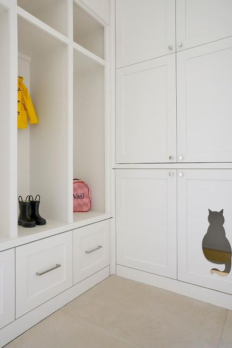 Charming white mudroom stands out with wall to ceiling white shaker cabinets finished with a cat shaped cut out leading to a well concealed litter box as an adjacent wall features open lockers positioned under cubbies and above pull out drawers accented with satin nickel pulls. Transitional Laundry Room, White Shaker Cabinets, Mudroom Design, Cabinet Finishes, Shaker Cabinets, Cat Door, Laundry Mud Room, Laundry Room Design, Mud Room