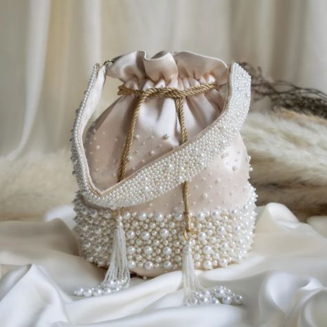 This statement piece is embellished with a very broad pearl border and finished off with tassels. It also includes a matching pearl embellished handle. not given not given Silk Fancy Clutch Purse, Fancy Clutch, Drawstring Bag Pattern, Bridal Handbags, Potli Bag, Sewing Easy Diy, Step By Step Crochet, Stylish Tote Bag, Potli Bags