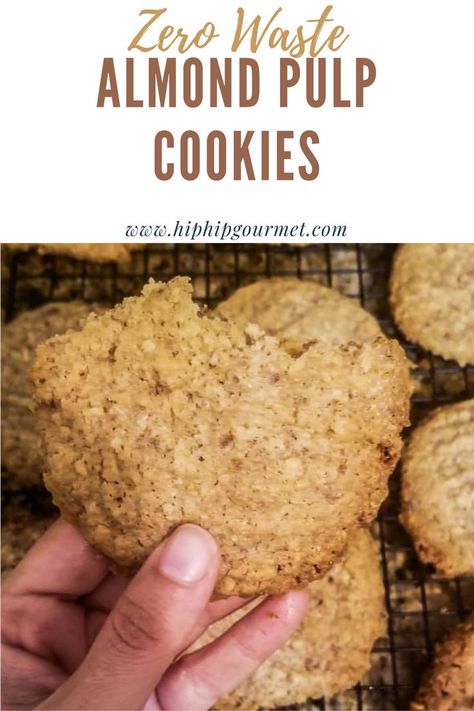 hand holding up one almond pulp cookie over a dozen more cookies on a wire rack Leftover Almond Pulp, Almond Pulp Bread Recipes, Nut Pulp Cookies, Almond Milk Cookies, Oat Pulp Cookies, Walnut Pulp Recipes, Leftover Almond Pulp Recipes, Almond Milk Pulp Recipes, Nut Pulp Recipes