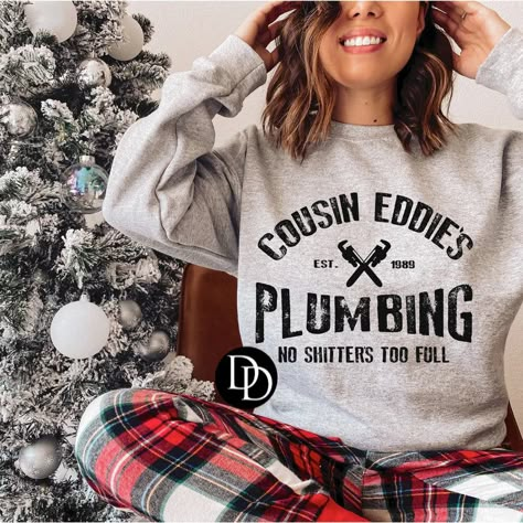 Women's Christmas Crewneck Cousin Eddie's Plumbing Graphic Yule love this soft and cozy Christmas crewneck! It's just the right mix of festive and funny, featuring Cousin Eddie's iconic catchphrase. Perfect for a holiday outfit with a sense of humor! Peep our other Christmas Graphics here! Details Available in sizes XS - 2XL Available in Heather Red, White or Ash Gray Crewneck Sweater "Cousin Eddie's Plumbing - No Shitters Too Full" graphic Round Neckline Fabric 52% Cotton / 48% Polyester Sizing Sweatshirt Shirts, Cousin Eddie, Christmas Graphics, Grey Crewneck, Holiday Outfit, Adulting Shirts, Sense Of Humor, Christmas Tees, Embroidered Sweatshirts