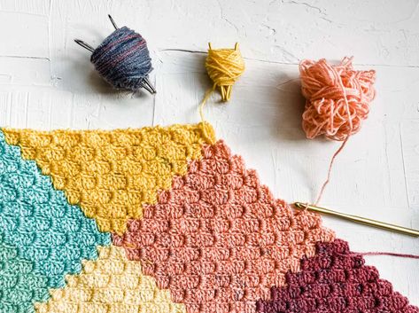 Flat lay of a multi-colored corner-to-corner crochet blanket with three different colored yarns and a crochet hook. C2c Patchwork Blanket, C2c Jayg Blanket, Corner To Corner Crochet Blanket, Corner To Corner Crochet Pattern, Bow Crochet, Crochet Granny Square Tutorial, C2c Crochet Blanket, Corner Crochet