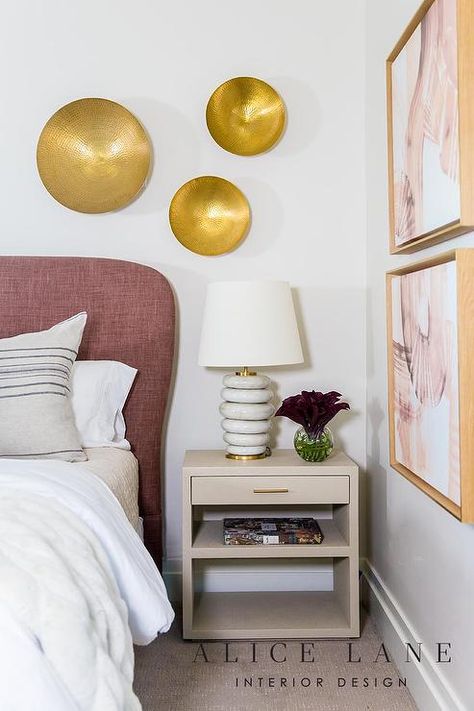 Chic bedroom updated with a mauve headboard and a light taupe nightstand displaying marble rings lamp under hammered brass wall decor. Gray Fabric Headboard, Grey Striped Walls, Brass Wall Decor, Gray Upholstered Headboard, Nailhead Headboard, Alice Lane, Marble Rings, Headboard With Lights, Grey Headboard