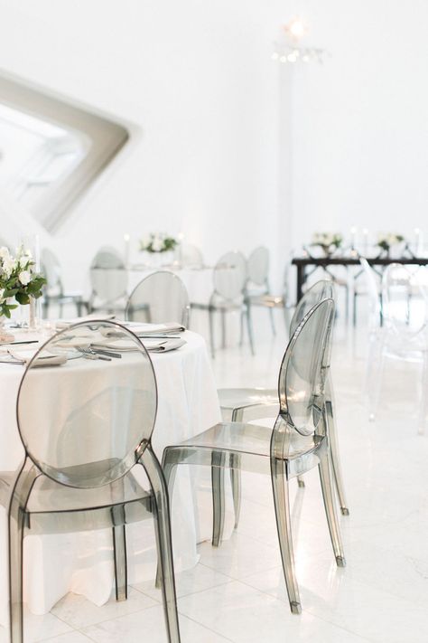 Wedding reception dining table with white linens, acrylic ghost chairs and lush and low floral arrangements. Ghost Chairs Wedding Reception, Low Floral Arrangements, Ghost Chair Wedding, Wedding Reception Chairs, Acrylic Dining Chairs, Clear Chairs, Art Museum Wedding, White Linens, Acrylic Chair