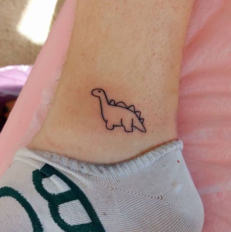 Small Cartoon Dinosaur Tattoo, Dinasour Tattoo Tiny, Cartoon Dinasour Tattoo, Dinosaur Ankle Tattoo, Cute Dinosaur Tattoos For Women, Cute Dino Tattoo Ideas, Small Dinasour Tattoo Ideas, Dino Stick And Poke, Small Stegosaurus Tattoo