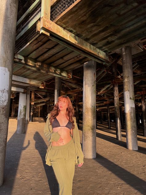 Girl standing under pier at beach posing for picture during golden hour and wearing a green two piece set cover up with bikini Pier Beach Pictures, Under Pier Photoshoot, Pier Picture Ideas, Beach Pier Photoshoot, Pier Photoshoot Ideas, Pier Pictures, Pier Photoshoot, Pier Photos, Pool Photography