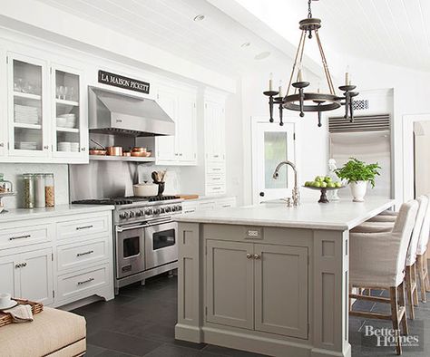 A pitched kitchen ceiling gets even more attention with tongue-and-groove paneling. Slate flooring grounds the kitchen, while white cabinetry and a marble backsplash leave the room feeling light and airy. Gray paint on the island brings in a new hue without distracting from details like the statement chandelier. Greige Island, Greige Kitchen Cabinets, Neutral Kitchen Designs, Greige Kitchen, Gray Island, Gray And White Kitchen, Neutral Kitchen, Kitchen Ceiling, Marble Counter