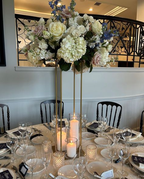 An elevated blush and white wedding centerpiece combines elegance and romance, creating a sophisticated focal point for your guest tables. Here we chose our gold Harlow stand with pillar candles in varying heights and gold rimmed votive candles for additional shimmer on the the tables. @tarrytownhouse Tall Flower Centerpieces With Candles, Elevated Wedding Centerpieces, Flower Centerpieces With Candles, Candle Votives Wedding, Votives Wedding, Tall Flower Centerpieces, Votive Candles Wedding, Elevated Wedding, Wedding Votives