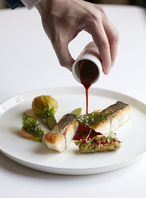 Hand pouring a red sauce over a plate with two fillets of seabass, a courgette flower, basil and prawn emulsion. Marcus Wareing, Restaurant In London, Fish Food, British Food, Cool Cafe, Sea Bass, Red Meat, Food Tours, Food Presentation