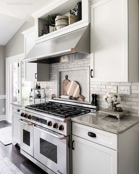 Subway tile wall is paired with a herringbone picture frame backsplash behind stove. Wood accents are displayed in front of the herringbone for an extra decorative touch. Stainless steel range is fit between white cabinets. Tile Backsplash Behind Stove, Backsplash Behind Stove Only, Unique Backsplash Ideas, Behind Stove Backsplash, Backsplash Behind Stove, Kitchen Niche, Herringbone Tile Backsplash, Mosaic Tile Kitchen, Patterned Tile Backsplash