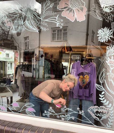 SARAH-VM-Interior-Stylist-Artist on Instagram: "FREEHAND ILLUSTRATION Loved working back in Guildford today. The lovely Kim from @mistyandclaridge sells the most beautiful designs. She wanted a bespoke design wrapping around two windows in her boutique. All designs are drawn inside for longevity, freehand, and painted in a custom colour palette to match the new Spring/summer collections arriving. Can’t wait to show you the final result 💕🌸🌿 #freehandillustration #illustration #illustratio Boutique Window Painting Ideas, Spring Painted Windows, Painted Store Windows, Storefront Window Painting, Spring Window Art, Window Display Design Creative, Summer Window Painting, Spring Window Painting, Spring Window Display