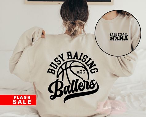 "Basketball Mama Sweatshirt, Busy Raising Ballers, Somebodys Loud Mama, Basketball Crewneck, Basketball Mom Shirt, Game Day Shirt, Sport Mom 📋 HOW TO ORDER: 1. Select the size 2. Select the color 3. Select the quantity 4. Add personalization if required 5.Add to Cart (\"buy now\" will take you directly to checkout and \"add to cart\" will allow you to continue shopping with us) 6. Submit order (Shipping will automatically be combined for you) Always FREE SHIPPING on orders of $35 or more 👚G A R M E N T ∙ F E A T U R E S : - Our unisex mid weight cozy sweatshirt is is super soft -Made with air jet yarn for softer feel and reduced pilling -Pre-shrunk. -8 oz./yd² 50% preshrunk cotton, 50% polyester -Double-needle stitched collar, shoulders, armholes, neck, waistband and cuffs * All items ar Basketball Mom Outfit, Baseball Mom Outfits, Basketball Shirt Designs, Busy Raising Ballers, Raising Ballers, Basketball Mom Shirts, Basketball Sweatshirts, Baseball Sweatshirts, Winter Projects