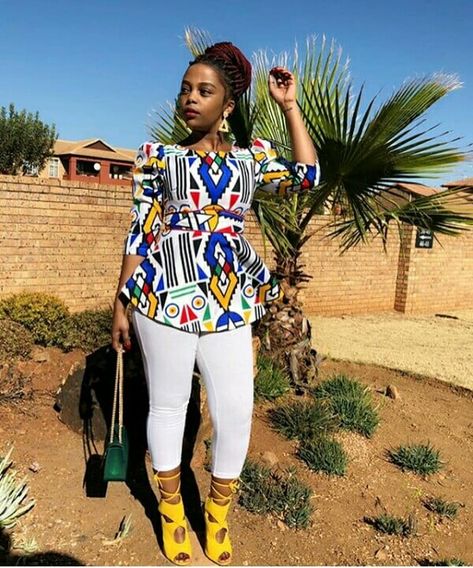 Clipkulture | Khanyi In Beautiful Ndebele Print Blouse With White Leggings and Yellow Strap Sandals Traditional Attire South Africa, Ndebele Print Outfits, Crazy Tops, Ndebele Traditional Attire, Ndebele Print, Kitenge Tops, Ankara Blouse, African Traditional Wear, African Blouses