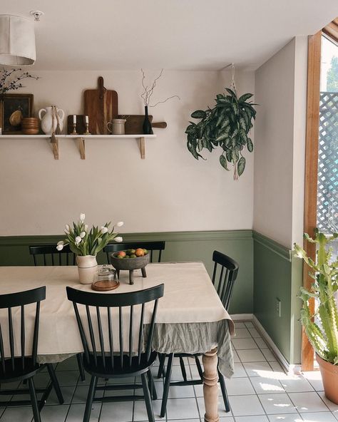 Depart from traditional colors in favor of a more vibrant look by painting your wainscoting an unexpected color, like the gorgeous green in this dining room. This colorful detail can be paired with white upper walls to give the room a unique personality. Shelving and hanging plants are perfect accessories to accompany green wainscoting. Half Painted Walls Kitchen, Dining Room With Green Accents, Wainscoting Ideas Paint, Dining Room Green Wainscoting, Half Painted Dining Room, Black And White Kitchen With Green Accents, Green Wainscoting Kitchen, Partial Wall Painting Ideas, Small Dining Room No Windows