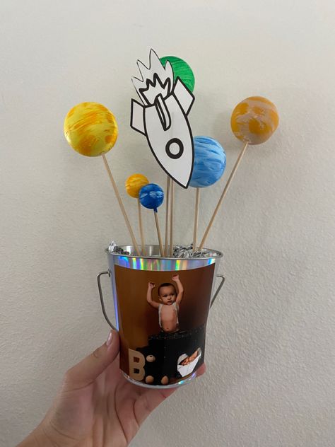 I ordered a pack of styrofoam balls off of Amazon with variations in sizes ! I stuck them to a kabob stick and painted them variation of colors to resemble planets. I then stuck it to styrofoam at the bottom of the pail I bought from the dollar tree ! The rocket ship I printed and cut out and then glued my sons picture to the Paul for an extra touch. They turned out so so cute and were so inexpensive and easy to make ! First Trip Around The Sun Centerpiece Ideas, First Trip Around The Sun Centerpiece, Sun Centerpiece Ideas, 1st Trip Around The Sun, Sun Birthday, Boys First Birthday Party Ideas, Boys 1st Birthday Party Ideas, First Trip Around The Sun, Centerpiece Ideas