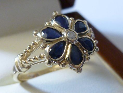 9CT/9K SOLID GOLD NATURAL SAPPHIRE & GENUINE DIAMOND FLOWER RING This beautiful Vintage inspired ring has been crafted in 9ct Solid Yellow Gold Each bezel set petal of this Floral ring has a NATURAL Sapphire and an Earth Mined prong set Diamond in the centre (COLOUR: G & CLARITY: SI). The wishbone shoulders have been beautifully decorated. THIS VINTAGE INSPIRED SAPPHIRE/DIAMOND BLOSSOM RING IS TRULY AN EXQUISITE FINE JEWELLERY PIECE WHICH IS TO BE TREASURED FOR A LIFETIME * FREE GIFT BOX Sapphire Flower Engagement Ring, Antique Sapphire Ring, Sapphire Flower Ring, Sapphire Ring Vintage, Diamond Flower Ring, Vintage Sapphire Ring, Vintage Inspired Rings, Vintage Sapphire, Opal Ring Gold