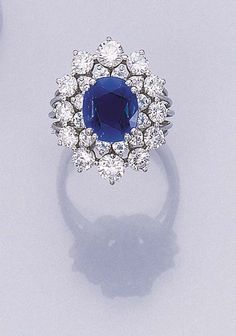 A SAPPHIRE AND DIAMOND CLUSTER RING   Set with a cushion-shaped sapphire weighing 3.25 carats in a circular-cut diamond surround to the wirework platinum hoop Cluster Ring Set, Colored Stone Rings, Fine Diamond Jewelry, Unique Diamond Rings, Jewels Rings, Sapphire Engagement Ring Blue, Diamond Engagement Ring Set, Ladies Diamond Rings, Blue Gems