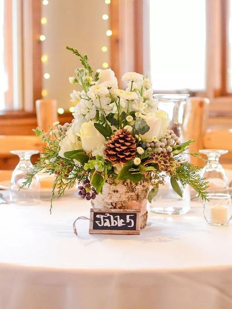 a cozy and rustic winter wedding centerpiece of a tree stump, greenery and evergreens, white blooms, berries and pinecones Simple Wedding Table Decorations, Low Wedding Centerpieces, Christmas Wedding Centerpieces, Winter Wedding Table, Winter Wedding Centerpieces, Winter Centerpieces, Rustic Winter Wedding, Wedding Themes Winter, Winter Wedding Decorations