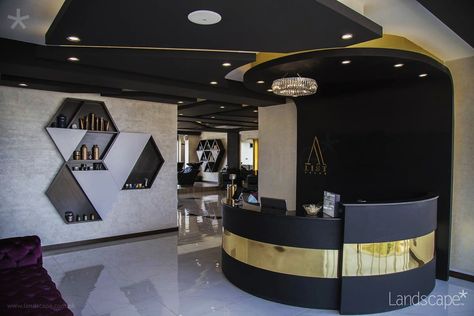 Entrance/Reception of a high-end salon, designed and built by Landscape PLC, featuring monochrome angular ceiling, gold finish reception desk and hexagon products' display wall. Stay tuned for more views! #landscapeplc #saloninterior #interiordesign #gold #finish #reception #displaywall Black And Gold Reception Desk, Reception Desk Design Entrance, Grey Reception Desk, Interior Design Entrance, Luxury Reception Desks, Stone Reception Desk, Gold Interior Design, Reception Ceiling, Gold Reception