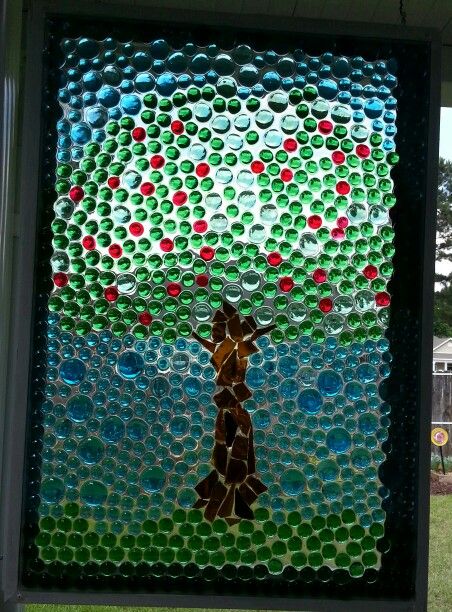 My apple tree faux stained glass window.  Used an old window, flat glass marbles and pieces from a broken wine bottle for the trunk.   Cover the whole thing with an epoxy gloss coat (comes in a two part kit).  Kits cost about $25 at Home Depot and Lowe's.  A one quart kit can cover about 6 square feet.  I did not glue the marbles to the glass first.  Just laid them on the glass.  Darker marble colors look best.  This is even better in person IMHO.  :) Glass Pebbles Ideas, Broken Wine Bottle, Vitromosaico Ideas, Faux Stained Glass Window, Flat Marbles, Tree Faux, Window Crafts, Glass Pebbles, Window Projects