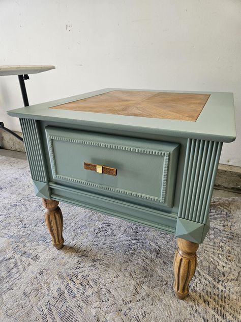 Beautiful vintage table refinished with modern accents.  Sage Green Natural wood Gold Accents New Hardware 1 drawer White and gold leaf lining in drawer Natural wood legs highlighted with custom finishing Measurements: 24" Tall,  28" deep,  26" wide Delivery available within 50 miles of Forty Collins for an additional fee. Message me for arrangements End Table Refurbish, Vintage Nightstand Makeover, Side Table Refurbish Ideas, Side Table Flip Ideas, End Table Flip Ideas, Green Painted Nightstand Ideas, Vintage Phone Table Makeover, Green Painted Nightstand, Vintage End Table Makeover