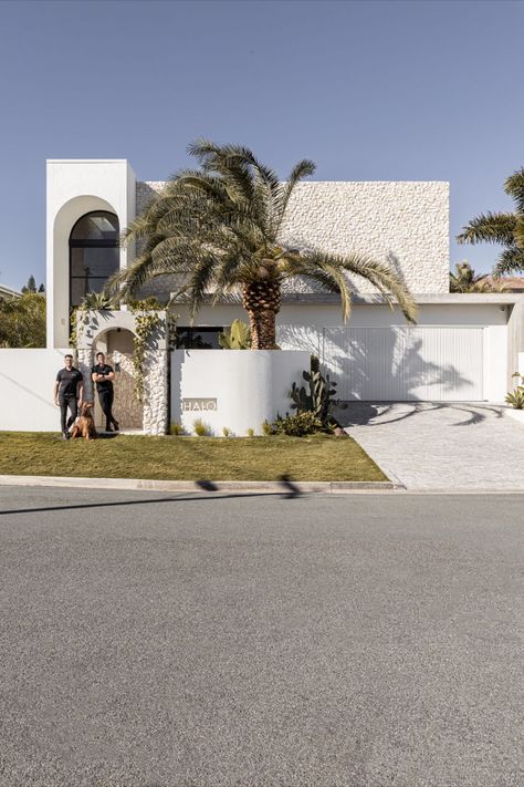 A Mediterranean-inspired facade which features an abundance of stone and a large palm tree. Hampton House Exterior, Mediterranean Architecture Modern, Gunmetal Tapware, House Gates, Coastal Luxury, Abi Interiors, Privacy Wall, Gates Design, Mediterranean House