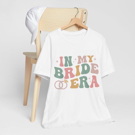 💍 Step Into Your Bride Era! 💍 👰 In My Bride Era Shirt 👰 Calling all brides-to-be! Celebrate your journey to "I Do" with the stylish and oh-so-chic "In My Bride Era" shirt. Perfect for all your pre-wedding festivities and beyond! ✨ Why You'll Love This Shirt: Elegant Design: Featuring a sophisticated and trendy design that highlights your special status. This shirt is the perfect blend of elegance and fun. Versatile and Stylish: Dress it up with a cute skirt or keep it casual with jeans. This Engagement Shirts, Bride Era, Bachelorette Party Shirt, Shirt Elegant, Engaged Shirts, Wedding Festivities, Bachelorette Party Shirts, Cute Skirts, Bridal Shower Gifts