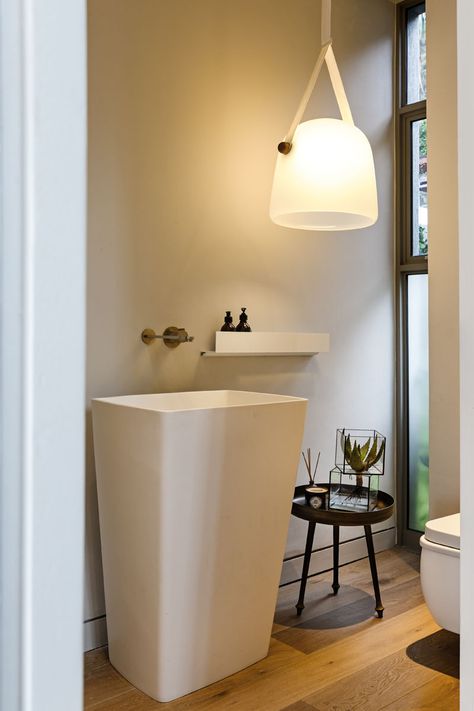 This modern bathroom has an oversized white pendant light, and a large white stand alone sink beside a set of windows. Stand Alone Sink, Sink Stand, Room Paint Designs, Over Toilet Storage, Vintage Laundry Room, Gym Bathroom, Sink Shelf, Large Tub, Laundry Room Bathroom