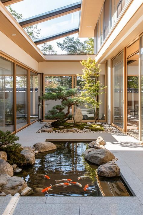 Modern japanese inner courtyard under a skylight roof with koi pond rocks and bonsai trees the house has large windows and shoji screen doors. Check out all of these Japanese courtyard houses that blend nature, minimalism, and tranquility to embrace full zen living. Garden In The Middle Of The House, Courtyard Koi Pond, Home With Courtyard In The Middle, Japanese Style Houses, Indoor Courtyard Ideas Modern, Pond In House, House With Courtyard In The Middle, Japanese Style Backyard, Courtyard Inside House