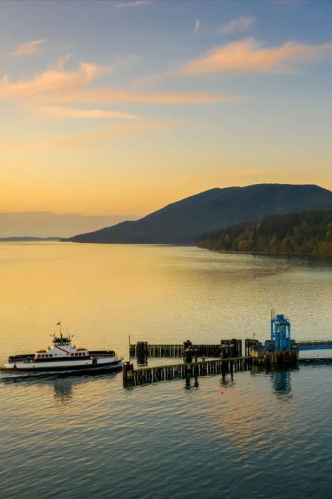 A small passenger ferry prepares to dock at tranquil Lummi Island. A forested mountain rises up out of the Salish Sea, with a light blue sky and wispy clouds above. The water ripples slightly, with the setting sun reflected in its surface. Bellingham Washington, San Juan Islands, Bike Riding, Creature Comforts, Best Kept Secret, Whale Watching, Take A Break, Art Galleries, Bird Watching