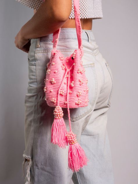 "📍Vibrant Pink Crochet Wayuu Bag * Make a stylish statement with this lively pink crochet Wayuu bag. Lovingly handwoven using premium cotton, this petite bag encapsulates the enduring spirit of Wayuu tradition. 🌸Approximate Dimensions * Height: 15 cm (5.9\") * Width: 12 cm (4.7\") * Strap Drop: 44 cm (17.3\") 🌷Features * Handwoven cotton construction with exceptional durability. * Adorned with shimmering faux pearl accents. * Vibrant pink hue exudes charm and flair. * Intricate weaving reflects renowned Wayuu technique. * Perfectly sized to carry small daily essentials. This vibrant bag keeps alive the incredible skill and passion passed down for generations by Wayuu artisans. ✨Add a pop of color and handcrafted artistry to any look with this one-of-a-kind bag. An effortless way to show Crochet Bucket Bag, Bags 2024, Handwoven Bag, Crochet Bucket, Crochet Tops Free Patterns, Wayuu Bag, Pink Crochet, Different Colours, Knitted Bags