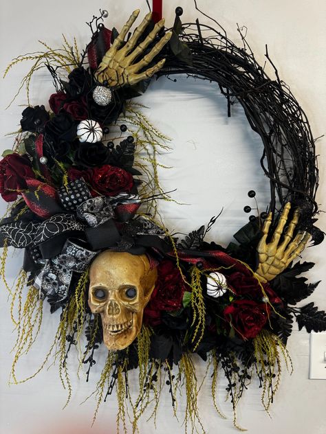 This beautiful Halloween wreath will take your decor to the next level.  A 24 inch grapevine is adorned with skeleton along with black and red florals.  Display on Your front door, over your fireplace or Interior walls will complement your Halloween Decor.  This wreath has a lot of black and red florals, sprays and greenery picks.  A large wired bow with skull and hands poking through and a rhinestone spider to add a touch of bling.  This has a over measurements of 36in x 30in x 9in. To ensure the longevity and quality of this wreath, display indoors or under a sheltered porch to protect from harsh weather conditions. This is not intended for extreme elements.  When not in use store in a cool dry place to maintain its condition.  Bows will need to be fluffed. Halloween Skeleton Wreath, Grapevine Halloween Wreath, Skull Wreath Diy, Halloween Grapevine Wreath, Halloween Skull Wreath, Mesh Projects, Wreath Display, Rhinestone Spider, Skeleton Decor