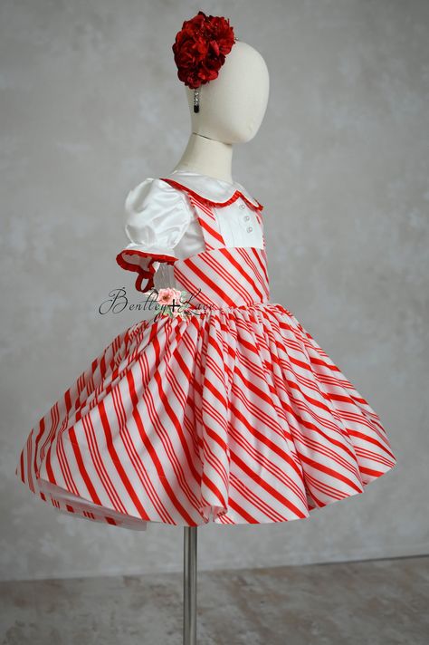 Step into the holiday spirit with our enchanting Candy Cane Lane Dress. Perfect for special holiday events and captivating photography sessions, this dress is designed to make you stand out. Crafted from custom-made striped stretch fabric, it features a delightful red and white candy cane theme, adorned with bridal soft tulle and satin for an extra touch of elegance and charm. An elastic attached back ensures a snug and comfortable fit, allowing for easy wear throughout your festive activities. The skirting is fully lined so not itchy feeling against the skin. (Colors shown may vary from screen/mobile device.) To view color chart will you need to zoom in or save the image. Please note: This fabric is custom made upon placing order and will need approximately 10-12 days to be made. This is Candy Cane Outfit, Candy Cane Dress, Candy Cane Theme, Editorial Dress, Captivating Photography, Festive Activities, Candy Cane Lane, Dress Couture, Couture Gown