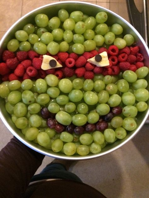 A ninja turtle fruit tray I made for my nephews bday.. I used a large cake pan did 2 layers of grapes and raspberries, then cut bananas for the eyes with chocolate chips for the pupils. ^.^ easy peasy... It took 1 box of SAMs club green grapes and 1 box of Sams raspberries. A few dark grapes and 1/2 a bananas.. ^.^ (I woulda done better on the eyes of i had more time! This was last min! Lol) #ninjaturtle #tmnt #party #fruittray #boys #birthday Ninja Turtle Fruit Tray, Tmnt Party Food, Turtle Fruit, Halloween Fruit Tray, Fruit Tray Ideas, Kindergarten Snacks, Ninja Turtle Birthday Cake, Fruit Platter Ideas Party, Turtle Birthday Parties