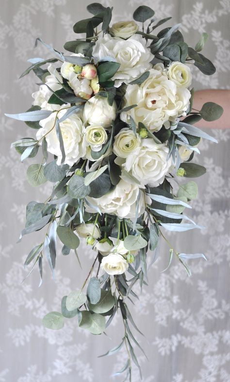 "CONGRATULATIONS on your upcoming wedding! This beautiful silk flower bridal bouquet is a romantic inspired ivory bouquet made with a stunning mix of faux/artificial flowers. Gorgeous greenery completes the look and all stems are flawlessly wrapped in ribbon of your color choice. Bouquet measures approx. 14\" in diameter by 24\" in length (although other diameters are available in drop down menu). Shown here tied with ribbon, but if you are interested in luxurious silk ribbon, this is available White Bouquet Bridesmaid, Bridal Bouquet Eucalyptus, Cascade Bridal Bouquet, Bouquet Eucalyptus, Ivory Bridal Bouquet, Holly Flower, Ivory Bouquet, Silk Flower Bridal Bouquet, Elegant Wedding Bouquets