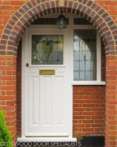 A multipoint locking 1930s door fully painted in pristine white and fitted into a brand new bespoke frame behind an attractive red brick archway. The pretty leaded glass pane features textured glass, coloured rondels and a delicate floral design in pink, green and lemon. A matching sidelight echoes the leaded glass design, while antique brass hardware completes the door’s beautiful heritage look. Installed with a modern multipoint locking system. Craftsman Style Front Door, Art Deco Front Door, 1930s Doors, American Craftsman Style, Victorian Doors, Brick Archway, Georgian Doors, Porch Lamp, Front Door Styles